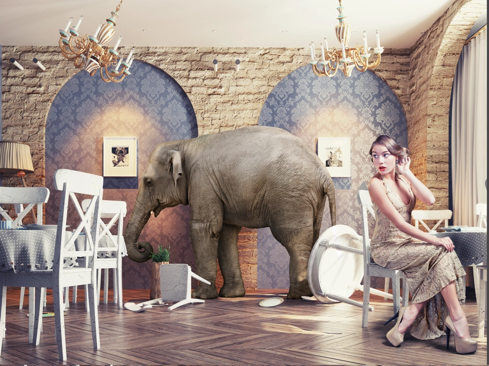 picture of a woman sitting in a restaurant with a giant elephant