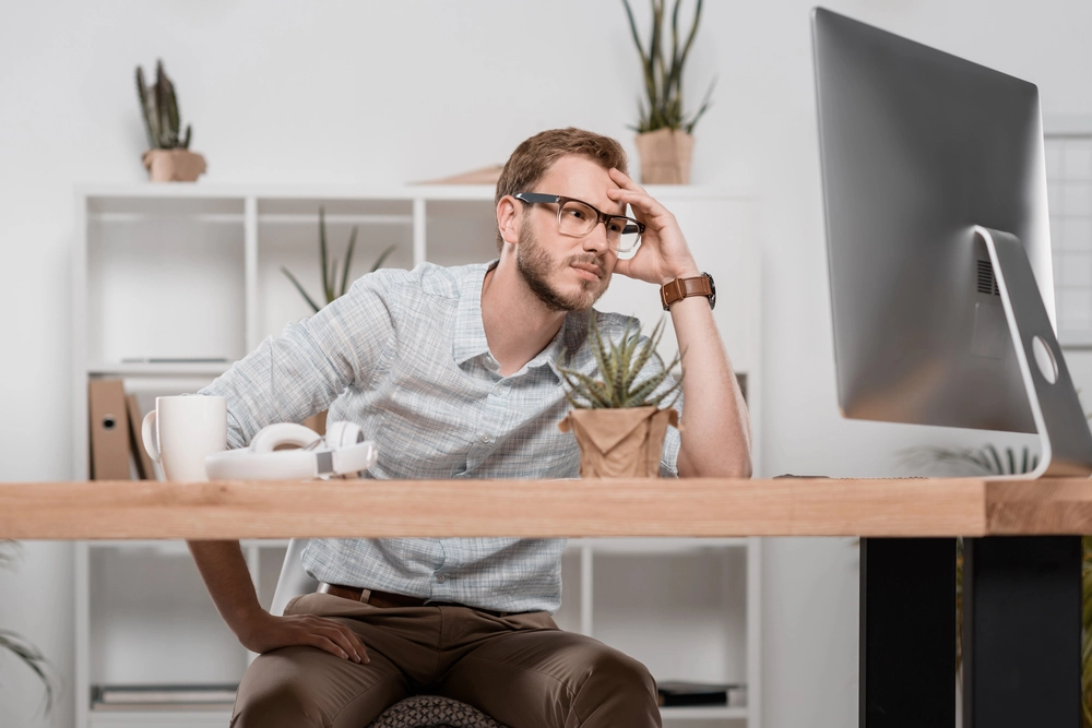 frustrated man staring at desktop computer monitor